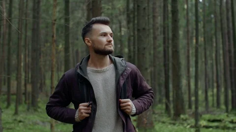 Portrait of man walking through trees in forest, traveler trekking in woodland Stock Footage 119045092