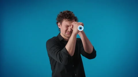 Portrait man watching through hand spyglass with comic blinking eye motion Stock Footage 176402252