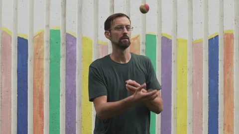Portrait of man while demonstrates juggling with three ball bags in slow motion. Stock Footage 94977485