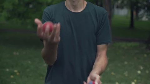Portrait of man while performs juggling tricks with balls, tilt up, slow motion. Vídeo Stock 95024350