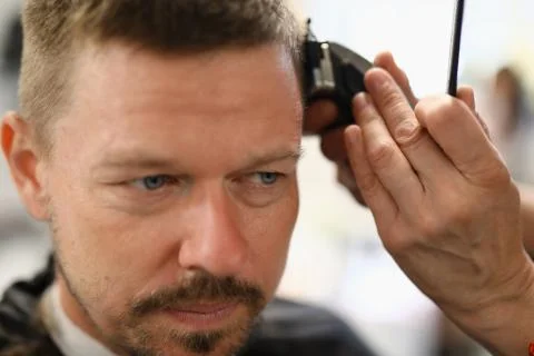 Portrait of man whose stylist cuts with hair clipper. Stock Photos