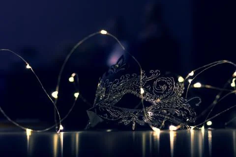 A portrait of a mask lying on a table surrounded by lights. The dark moody ev Stock Photos