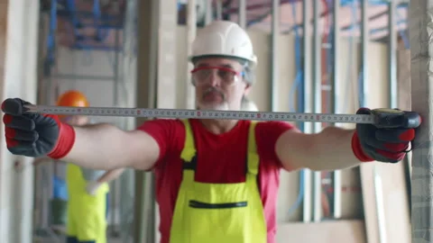 Portrait of mature builder using measuring tape at construction site. Realtime Stock Footage 168603273