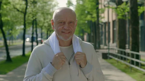 Portrait of the mature runner looking at the camera carries a towel around his Stock Footage 224706337