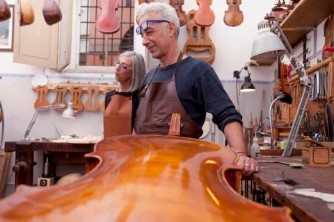Portrait of mature violin maker while testing the violins in his laboratory Stock Photos
