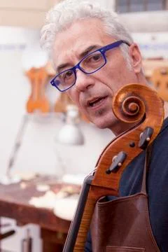 Portrait of mature violin maker while testing the violins in his laboratory Stock Photos