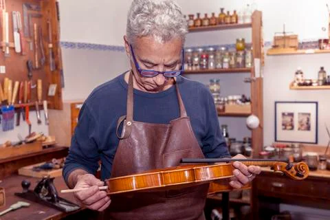 Portrait of mature violin maker while testing the violins in his laboratory Stock-Fotos