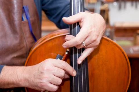 Portrait of mature violin maker while testing the violins in his laboratory Stock Photos