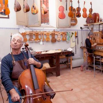 Portrait of mature violin maker while testing the violins in his laboratory Stock Photos
