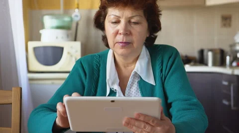 Portrait of a mature woman is using a tablet PC at home Vídeo Stock 59114245
