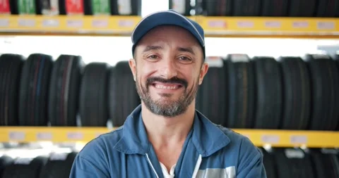 Portrait of Mechanic in work uniform looking camera at car tires shop service Stock Footage 157625222