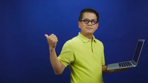Portrait of middle-aged asian man in casual yellow T shirt holding laptop Stock Footage 219469100