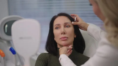 Portrait of middle-aged female client consulting with medical aesthetic Stock Footage 321059534