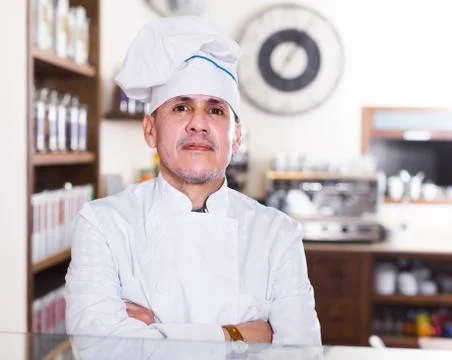 Portrait of middle aged man baker with tasty cakes smiling in bakery Stock Photos