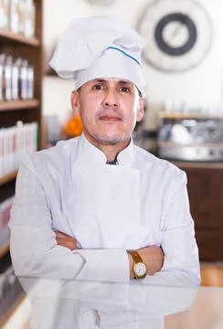 Portrait of middle aged man baker with tasty cakes smiling in bakery Stock Photos
