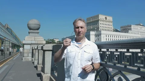 Portrait middle-aged man, bright sunny day, he stands bridge in sunny glasses Video stock 111773804