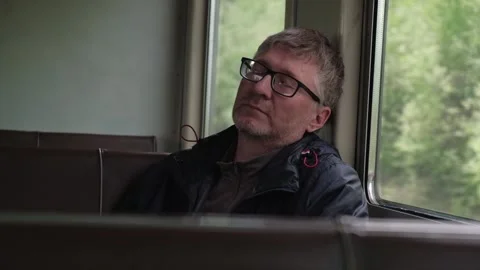 Portrait of middle aged man dozing off in commuter train carriage by window. Stock Footage 244242638