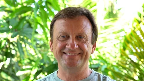 Portrait of a middle aged man resting on background of green leaves, close up Stock Footage 100651380