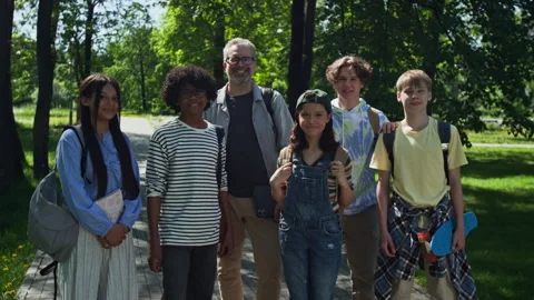 Portrait of Middle Aged Teacher with Multiethnic Teenagers Smiling in Park Stock Footage 339672818
