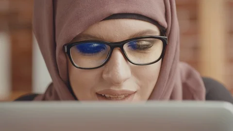 Portrait of a middle Eastern girl working at a laptop, her glasses reflecting Stock Footage