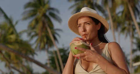 Portrait of Middle Eastern woman drinks fresh coconut under tall palms Stock Footage 346649819