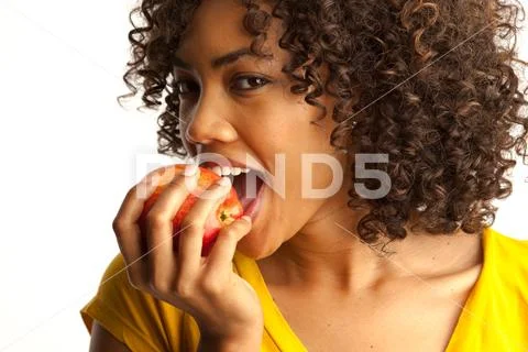 Portrait of millennial black woman taking bite of apple Stock Photos