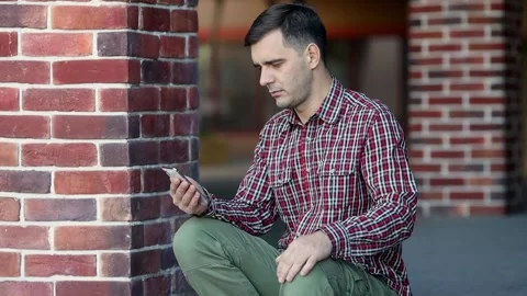 Portrait of a millennial man dialing a phone number on smartphone and calling Stock Footage 172573161