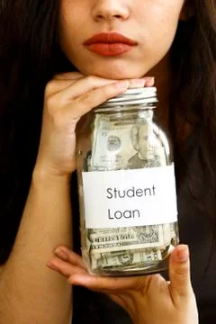 Portrait of mixed race woman holding jar of money for student loan Stock Photos