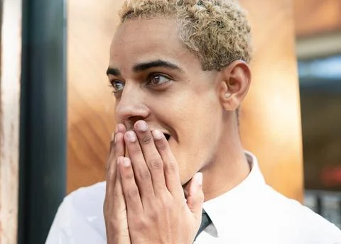Portrait of modern boy with surprised expression with his hands on his mouth Stock Photos