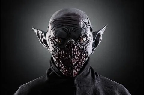 Portrait of a monster with sharp fangs over dark foggy background. Stock Photos