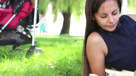 Portrait of a mother and child reading a book on the lawn. Stock Footage 41574419