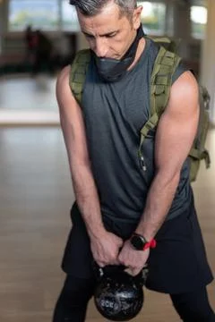 Portrait of motivated boot camp instructor stands with gym equipment in gym h Stock Photos