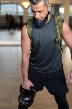 Portrait of motivated boot camp instructor stands with gym equipment in gym h Foto stock