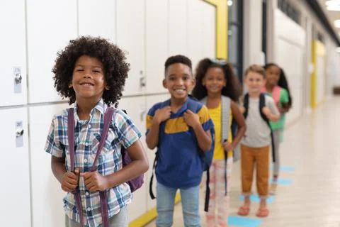 Portrait of multiracial smiling elementary school children with backpacks Stock Photos