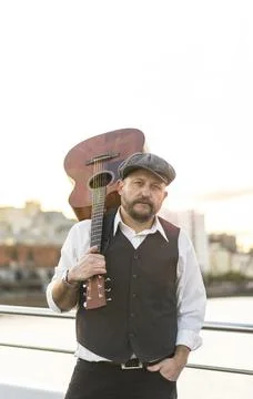 Portrait of a musician looking at camera while holding his guitar on his sh.. Stock Photos