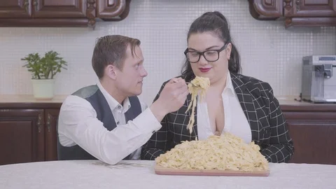 Portrait of a nerd guy and stylish plump woman in glasses sitting at a table Video stock 109536908