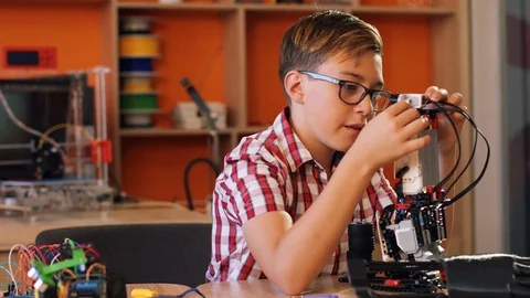 Portrait of nice blonde boy in glasses assembling a robot and then smiling Stock Footage 82490226