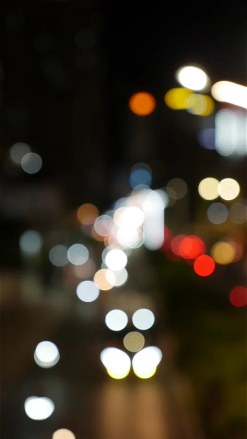 Portrait night scene with blurred headlights and taillights forming glowing Vidéo 333982585