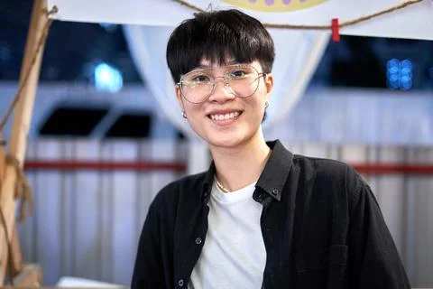 Portrait of a non binary person in casual clothes and glasses in a night market Stock Photos