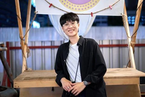 Portrait of a non-binary person smiling to the camera in an urban night fair Stock Photos