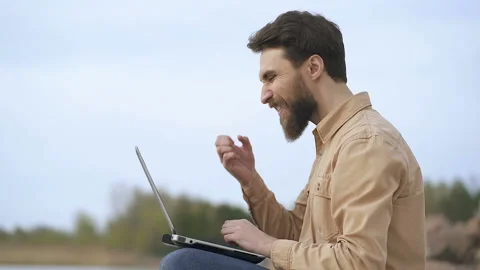 Portrait od beard man freelancing outdoors. Looking at the laptop, see good news Stock Footage 106638514