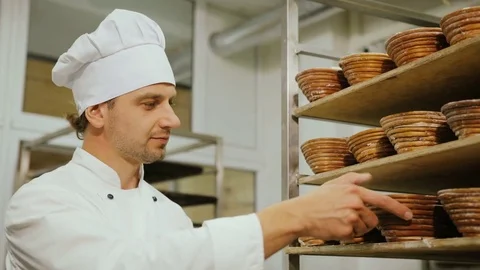 Portrait ofoung baker standing in his bakery in the morning and checking the Stock Footage