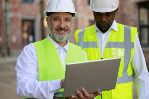Portrait ofthe two builders together standing, looking at construction area with Stock Photos