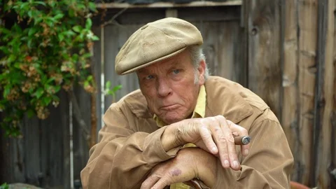 Portrait of old grumpy man holding cigar and leaning on his cane, looking Video stock 112274486