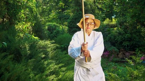 Portrait of an old lady training with a katana in the garden. Camera movement. Stock Footage 310332844