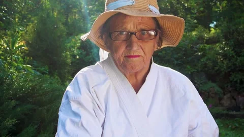 Portrait of an old lady training with a katana in the garden. Camera movement. Stock Footage 310332845