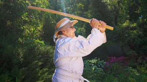 Portrait of an old lady training with a katana in the garden. Camera movement. Stock Footage 310332850