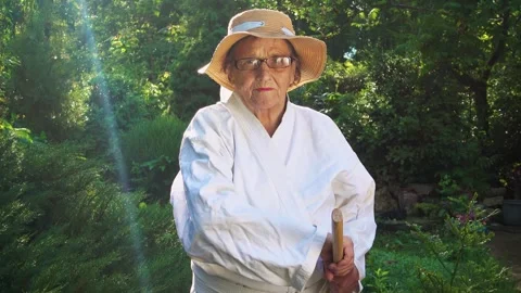 Portrait of an old lady training with a katana in the garden. Camera movement. Stock Footage 310332881