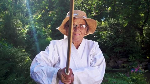 Portrait of an old lady training with a katana in the garden. Camera movement. Stock Footage 310332890