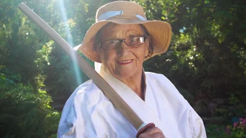Portrait of an old lady training with a katana in the garden. Camera movement. Stock Footage 310332904